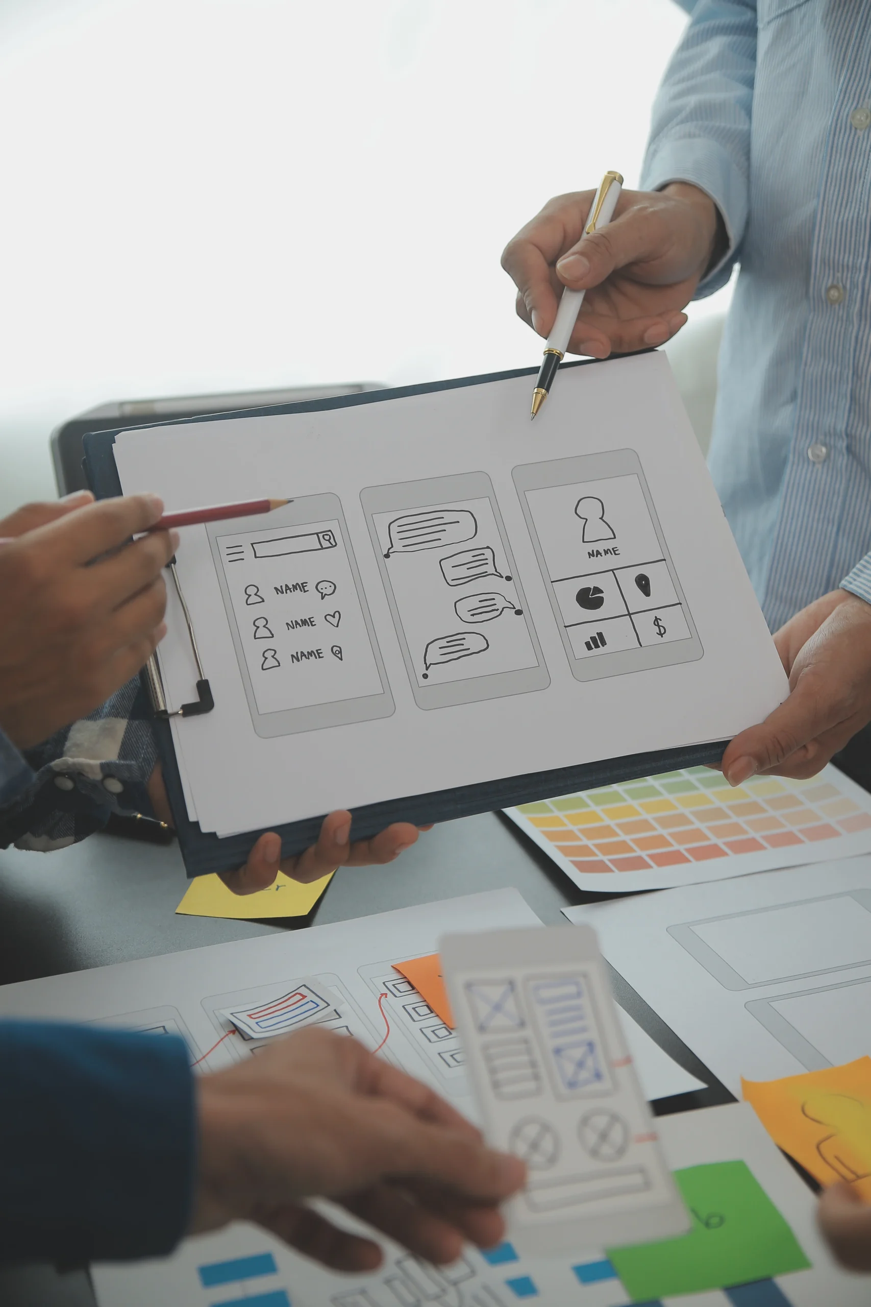 close-up-ux-developer-ui-designer-brainstorming-about-mobile-app-interface-wireframe-design-table-with-customer-breif-color-code-modern-officecreative-digital-development-agency